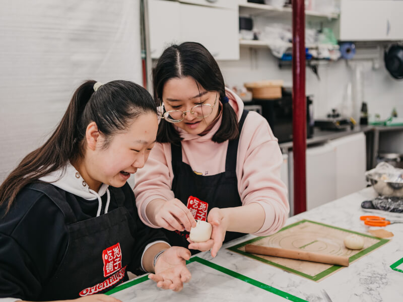 Two ladies enjoy a Chinese cooking class for making buns.